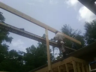 Carpenter setting a ridge beam over a new addition frame — Ice Dam Removal by Roofing Brothers in Sauk Rapids