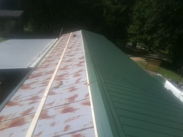Old rusted panels beside newly installed green metal roofing — Wind Damage Roof Repair by Roofing Brothers in Sauk Rapids