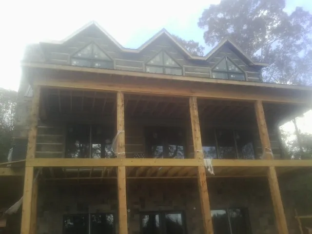 Dormers and porch framing on a large log home under construction — Roof Coating work by our crew in Sauk Rapids