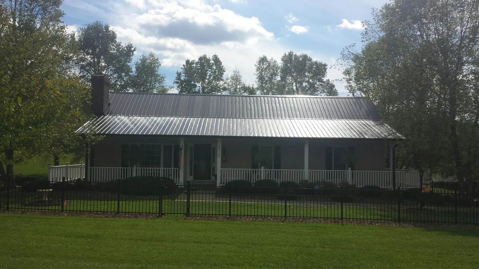 Gray metal roof on a brick ranch with a full width front porch — Gutter Guard Installation work by our crew in Sauk Rapids